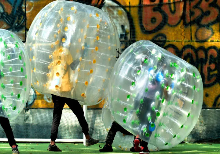 Players in inflatable bubble suits playing bubble soccer