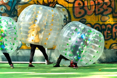 Players in inflatable bubble suits playing bubble soccer