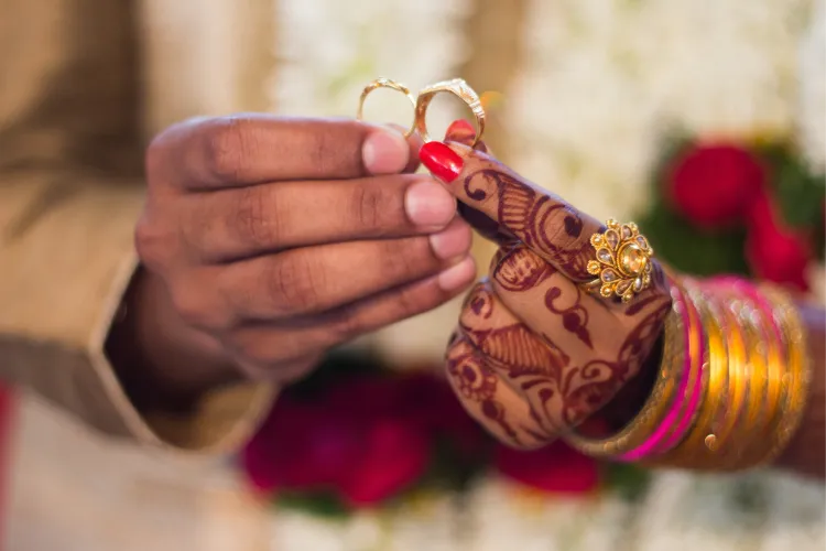 Couple exchanging rings with mehandi-decorated hands