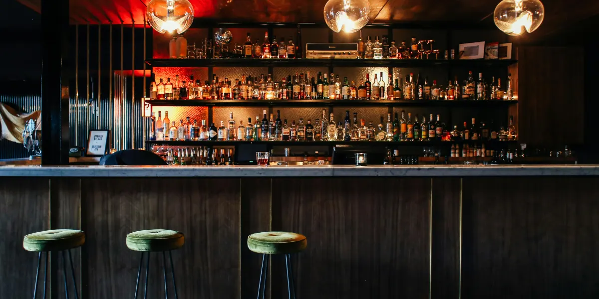 Bar counter with backlit bottle shelves at Frequency pub