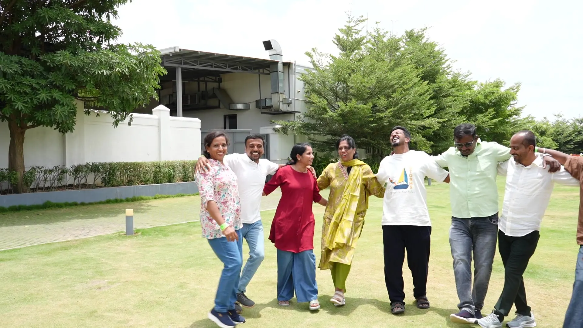 Team with arms linked on the lawn at a corporate outing