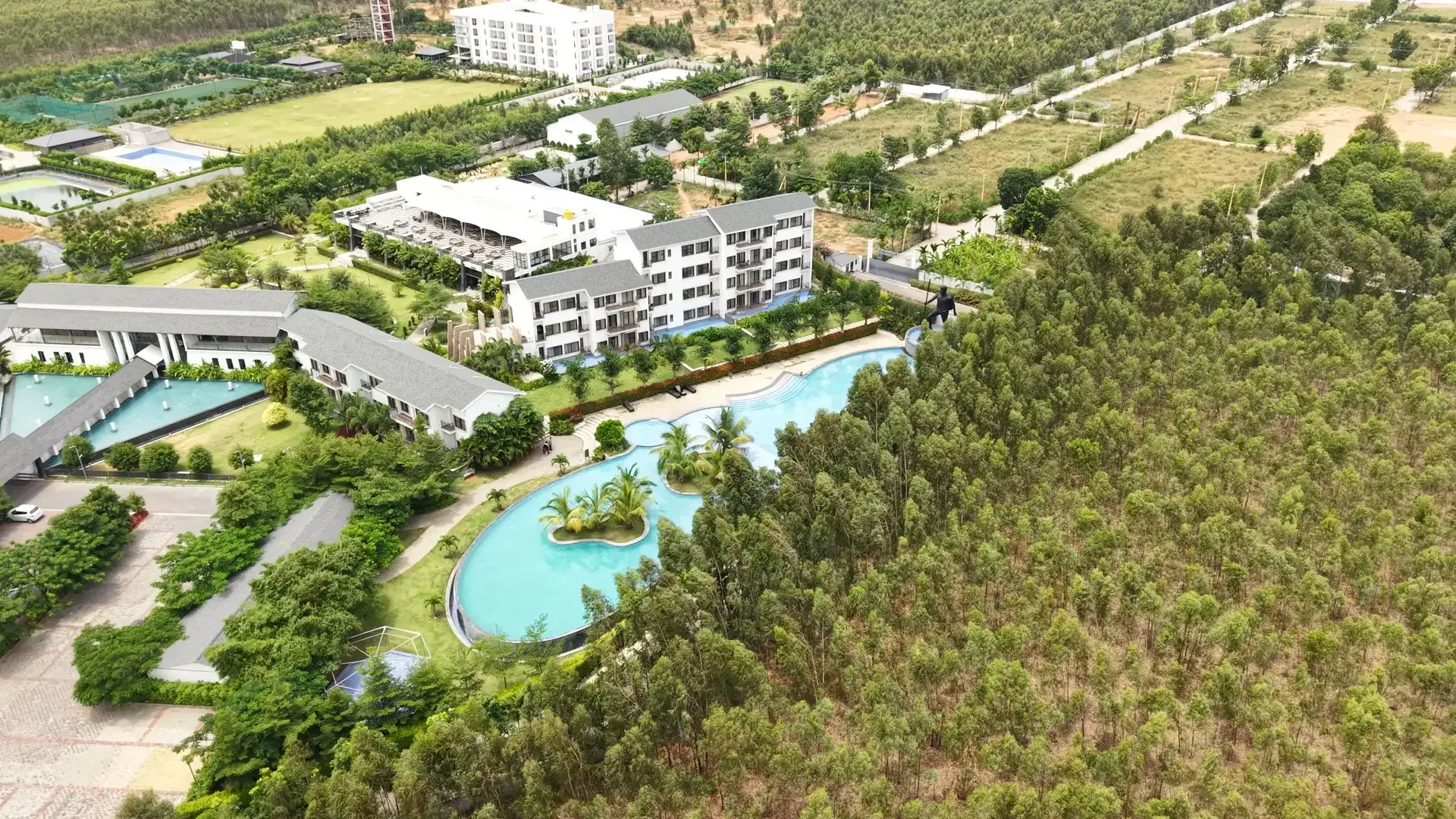 Aerial view of pool, lake and greenery at Sportico Resorts