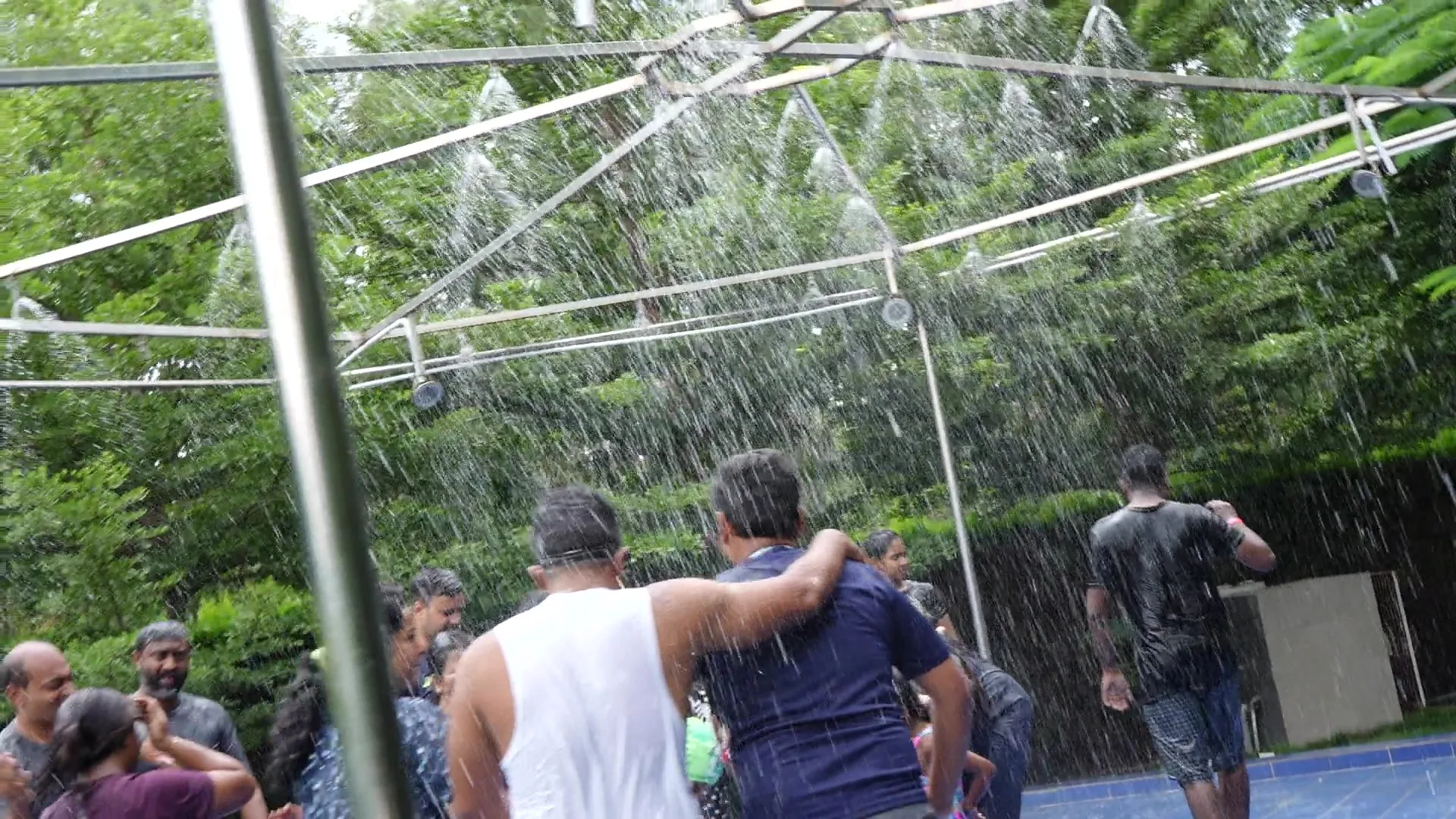 Friends laughing under the rain dance sprinklers