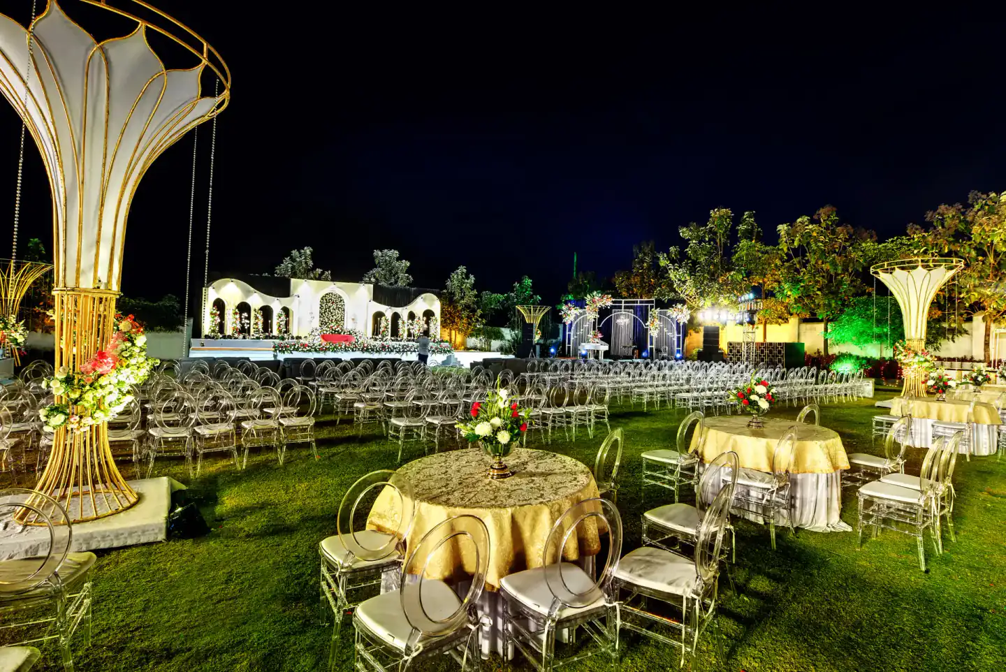 Gold décor and round dining tables at a night wedding on the lawn