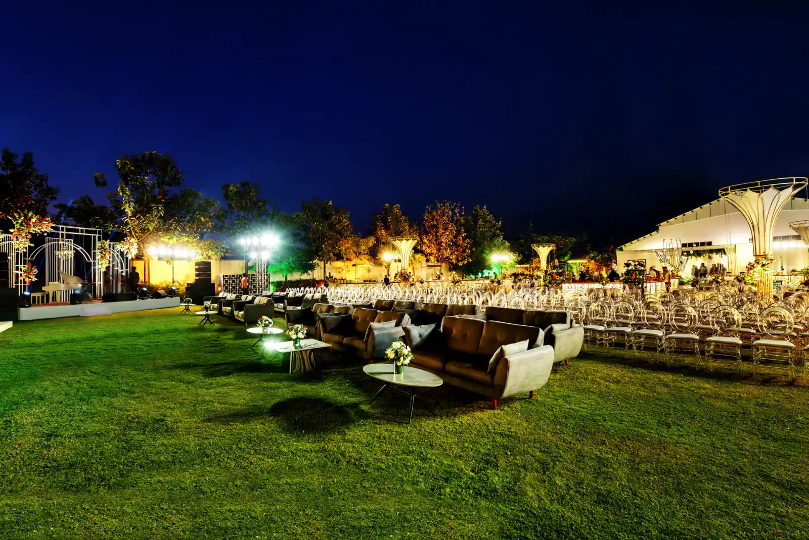 Lounge sofas on the lawn at a night wedding at Sportico Resorts