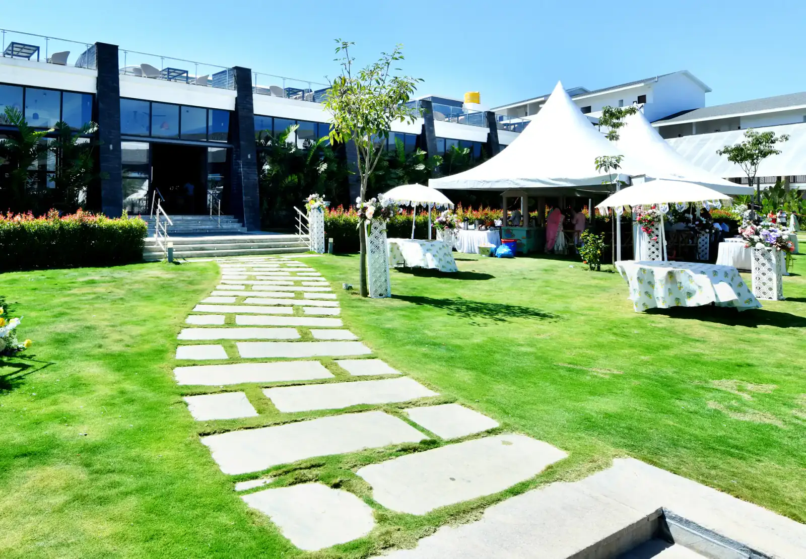 Lawn pathway and tents in front of the main building at Sportico Resorts