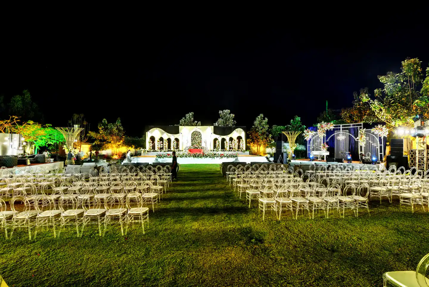 Lawn wedding seating with clear chairs facing the stage at Sportico Resorts