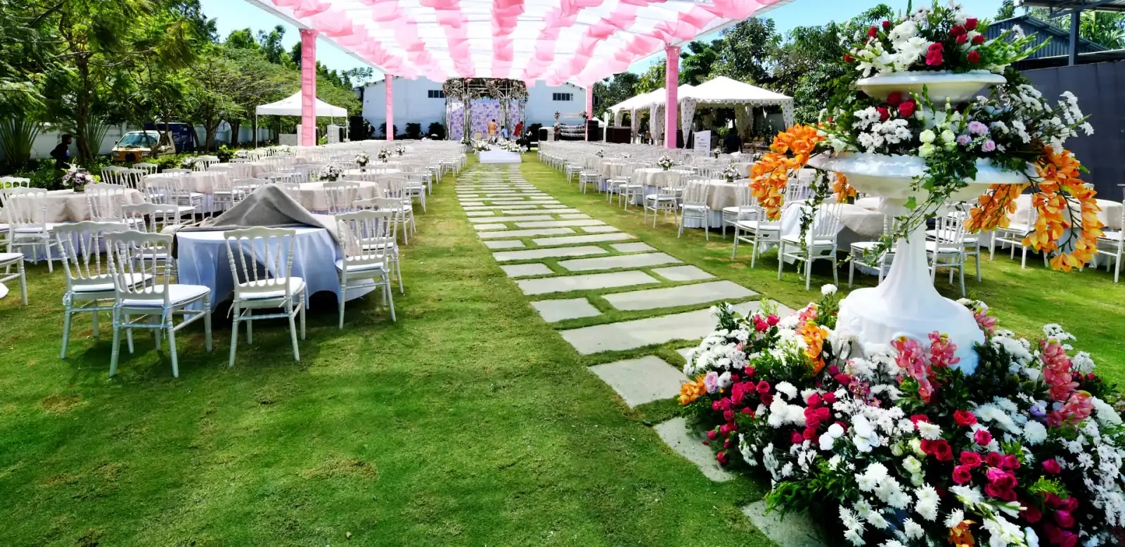 Dining tables under a pink canopy on the lawn at Sportico Resorts