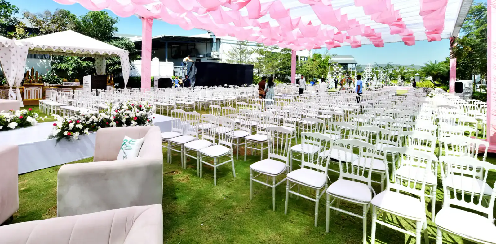 Rows of white guest chairs under a pink canopy on the lawn