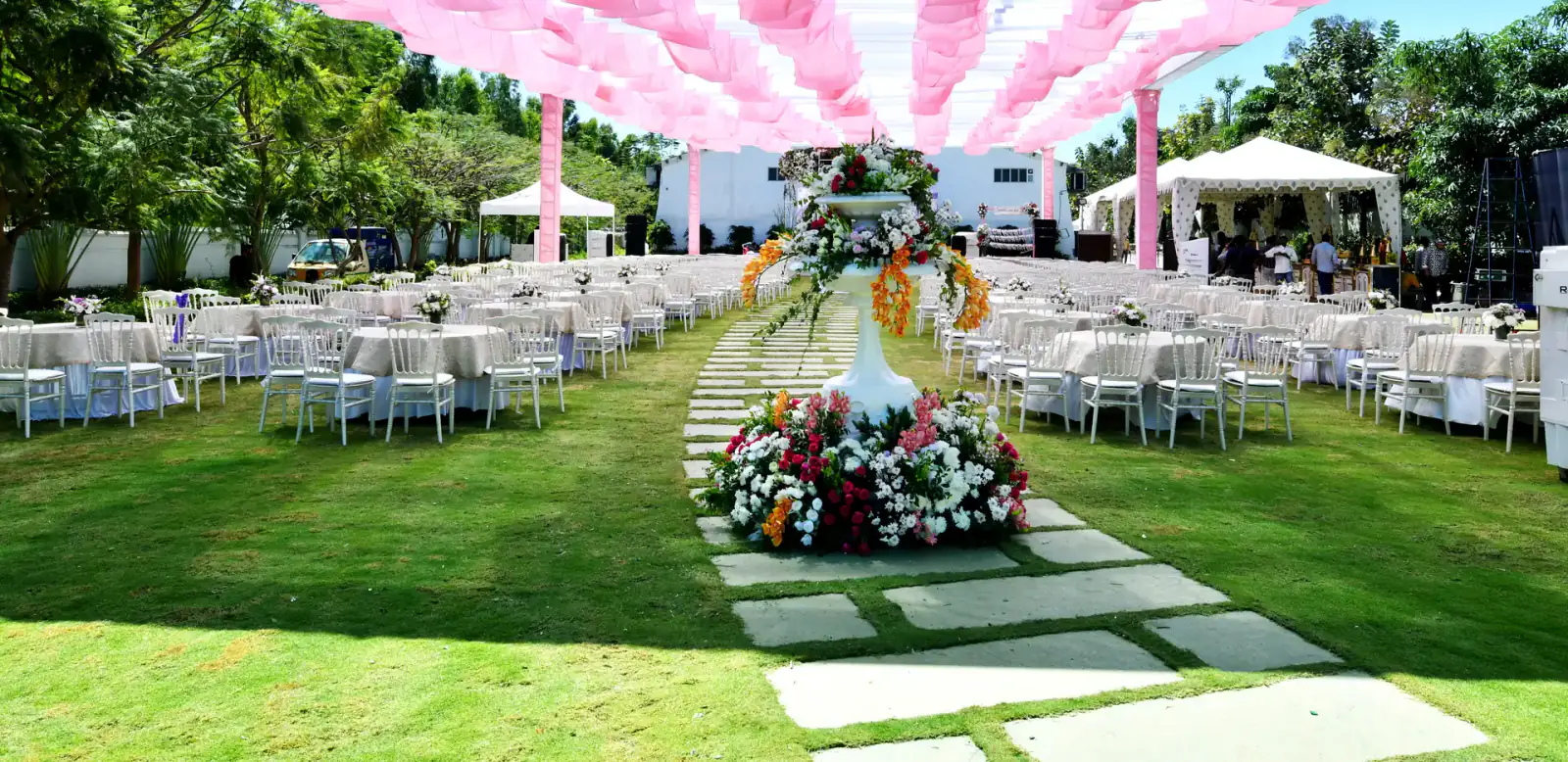 Pink canopy over the lawn aisle for a daytime wedding function